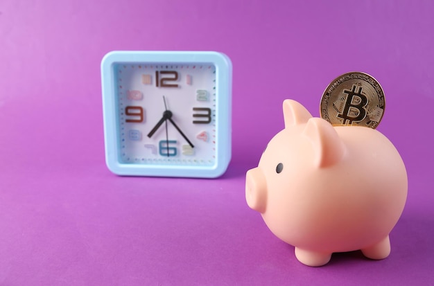 Cofrinho com bitcoin e relógio em fundo roxo Tempo é dinheiro