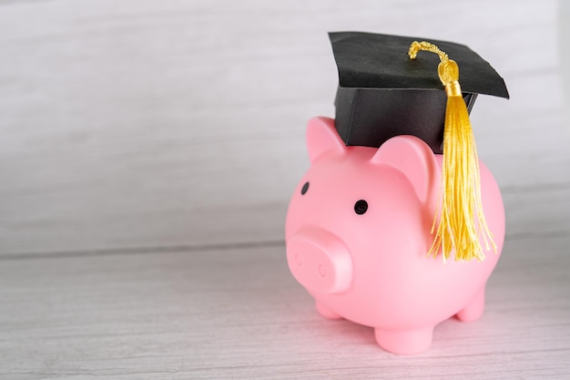 Cofrinho com chapéu de formatura Educação em finanças empresariais economizando dinheiro conceito de bolsa de estudos