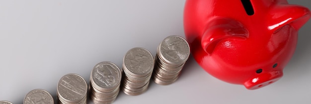 Cofrinho de porco vermelho e pilhas de moedas no conceito de acumulação de acumulação de mesa