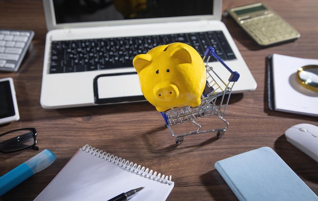 Cofrinho e carrinho de compras em cima da mesa