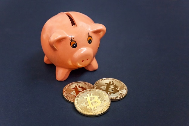Cofrinho e moeda de ouro bitcoin dinheiro virtual na mesa preta