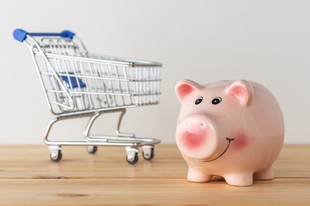 Cofrinho em uma mesa de madeira com carrinho de compras.