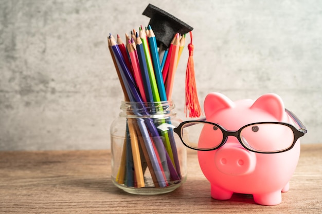 Cofrinho usando óculos com lápis coloridos, salvando o conceito de educação bancária