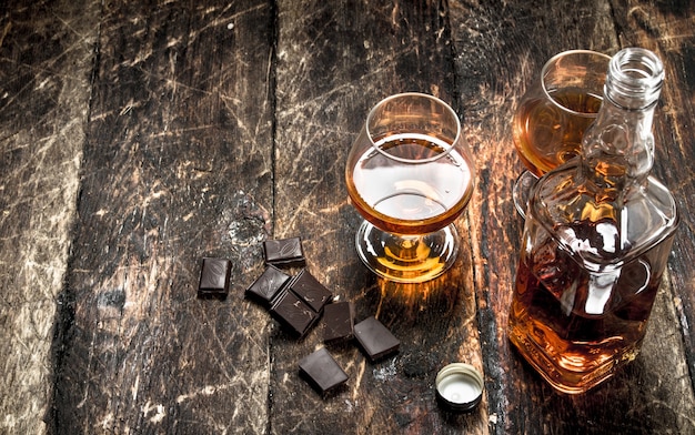 Cognac mit Bitterschokolade. Auf einem hölzernen Hintergrund.