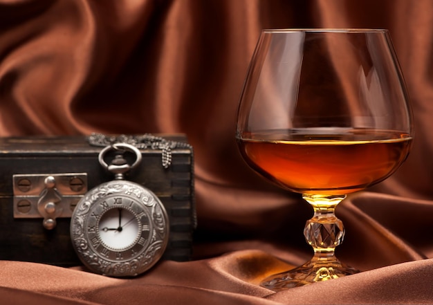 Foto cognac oder brandy und vintage-uhr an kette