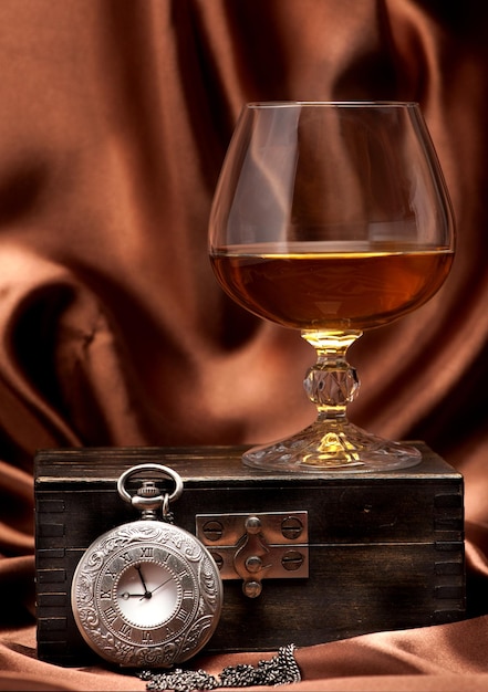 Foto cognac oder brandy und vintage-uhr an kette