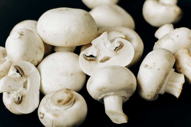 Cogumelos champignon em um fundo preto. espaço para texto