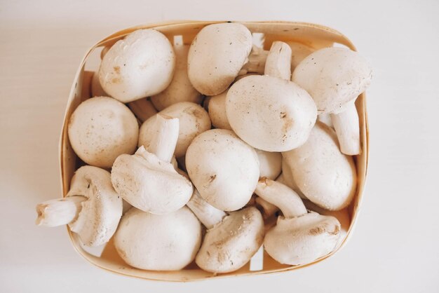 Cogumelos champignon em uma cesta de vime em um fundo branco