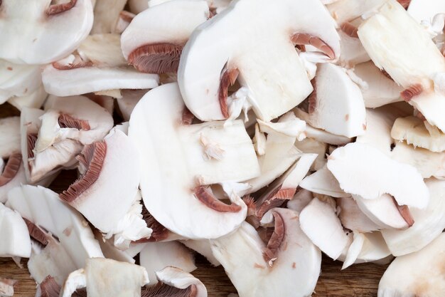 Cogumelos champignon fatiados durante o cozimento, close-up de cogumelos cortados para tratamento térmico