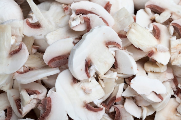 Cogumelos champignon fatiados durante o cozimento, close-up de cogumelos cortados para tratamento térmico