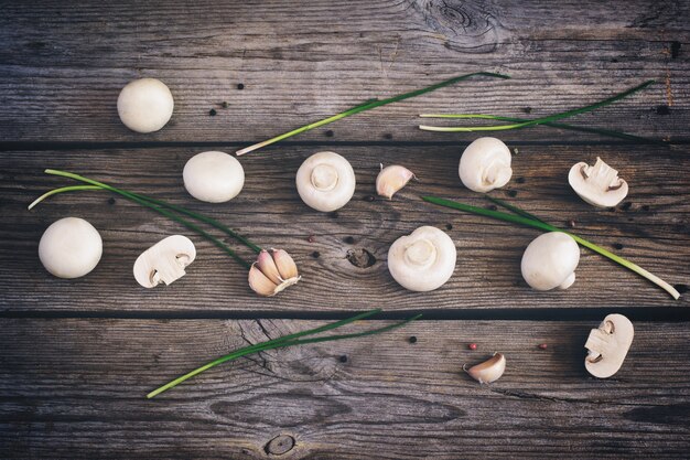 Cogumelos champignon, pimenta e ervas em um fundo de madeira velho