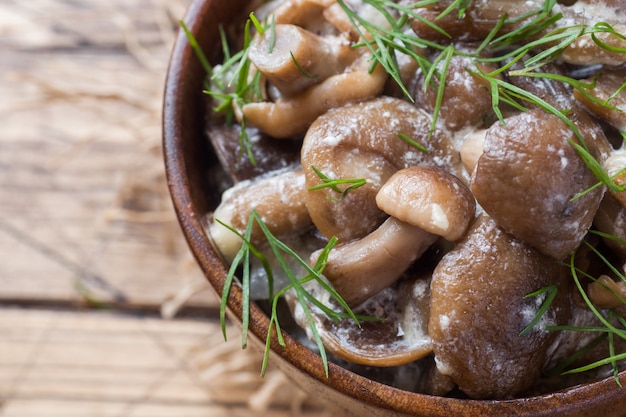 Cogumelos cozidos em um molho com creme de leite e queijo em uma tigela de madeira.