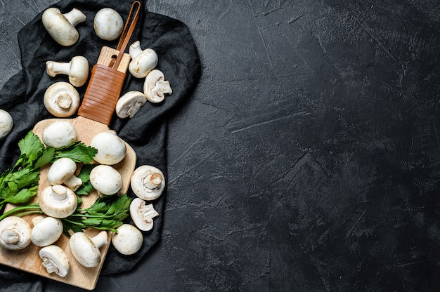 Cogumelos crus champignon em uma tábua de madeira.