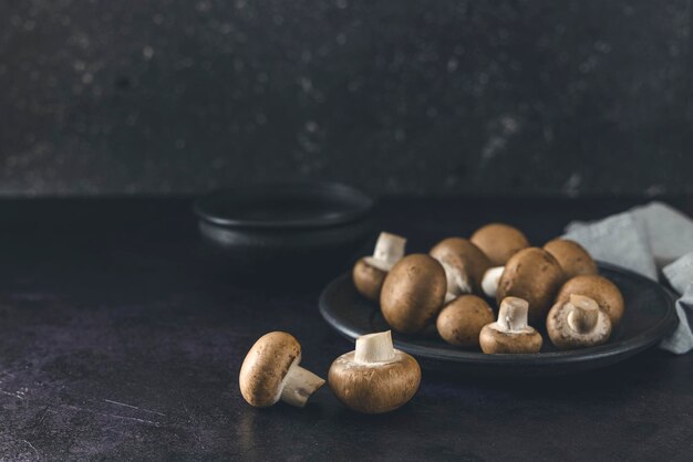 Cogumelos de cogumelos crus em fundo preto cozinhando champignons frescos