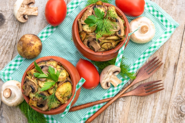 Cogumelos e batatas cozidos em panelas de barro no forno. na natureza com a adição de várias especiarias. vista do topo.