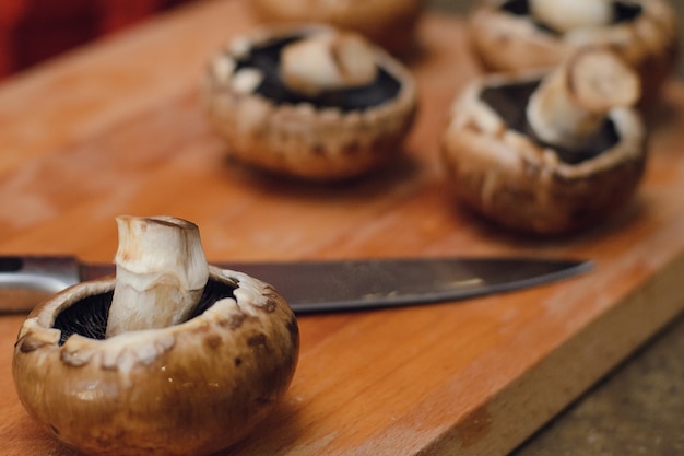Cogumelos em uma tábua de madeira ao lado de uma faca.