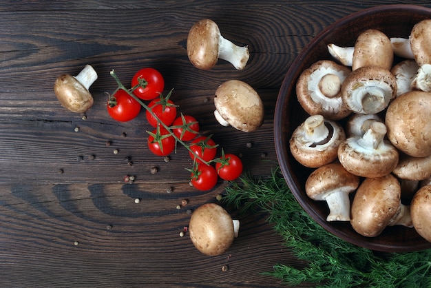 cogumelos frescos, champignon, tomate e especiarias em uma mesa de madeira.