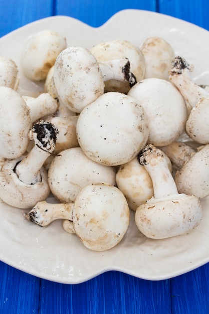 Foto cogumelos frescos em chapa branca na superfície de madeira