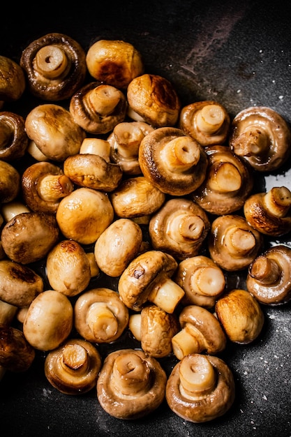 Cogumelos fritos pequenos em uma frigideira