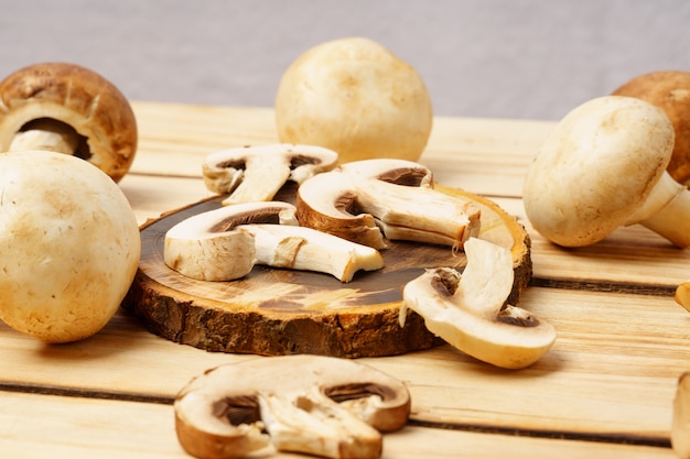 Cogumelos marrons. Pedaços de cogumelo em uma placa redonda de madeira, sobre um fundo de madeira