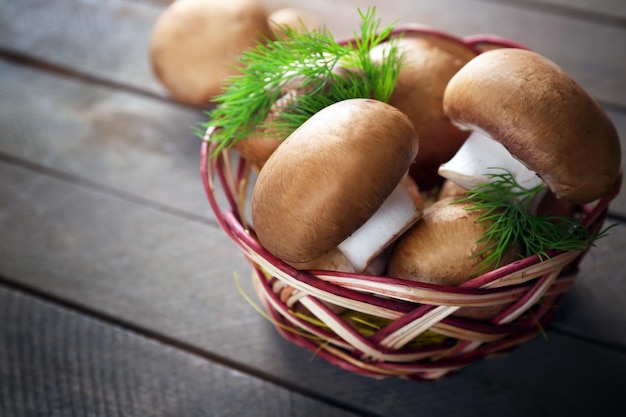 Cogumelos na cesta na superfície de madeira