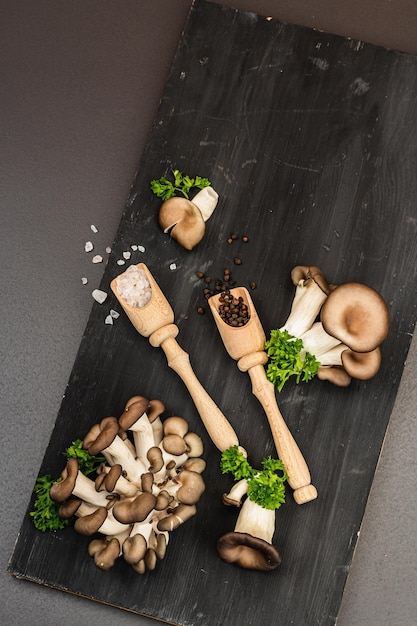 Cogumelos ostra orgânicos deliciosos com especiarias e salsa fresca na tábua de madeira Fonte de beta glucana pedra preta fundo de concreto vista superior