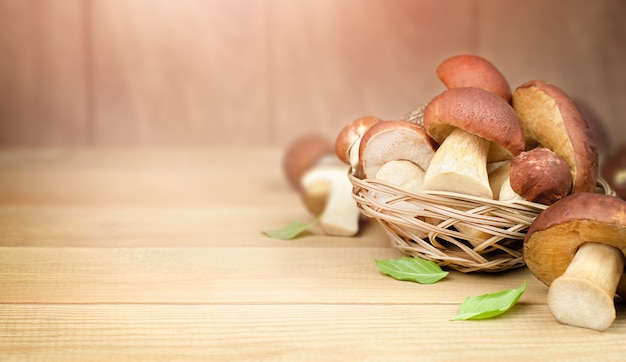 Cogumelos Porcini (cep) em uma cesta sobre uma mesa de madeira com um espaço de cópia