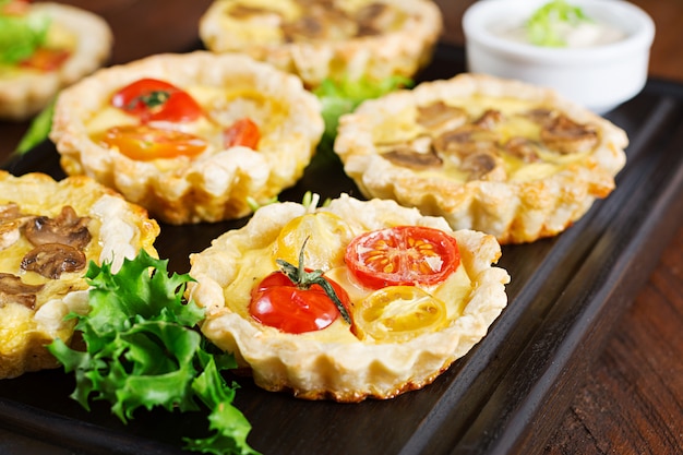 Cogumelos, queijo cheddar, tortinhas de tomate em madeira