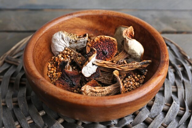 Foto cogumelos secos em tigela na esteira de vime closeup