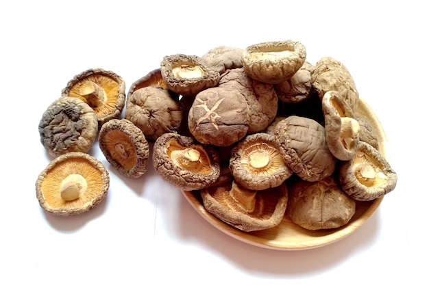 Cogumelos shiitake secos em uma placa de madeira sobre fundo branco