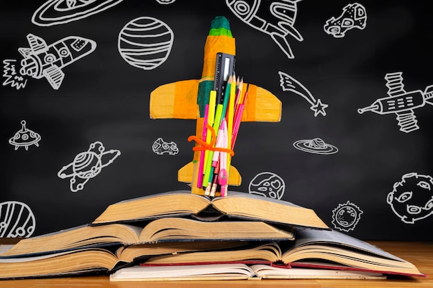 Cohete colocado sobre un libro frente a una pizarra que representa objetos espaciales en el aula