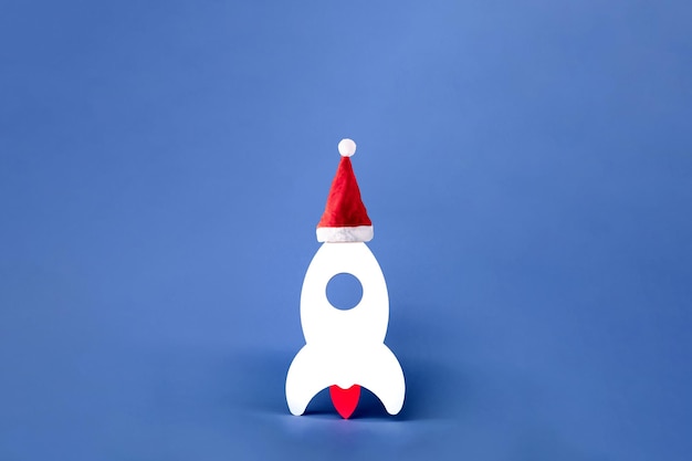 Cohete con sombrero de Navidad sobre fondo azul, concepto de negocio de inicio de año nuevo, diseño panorámico