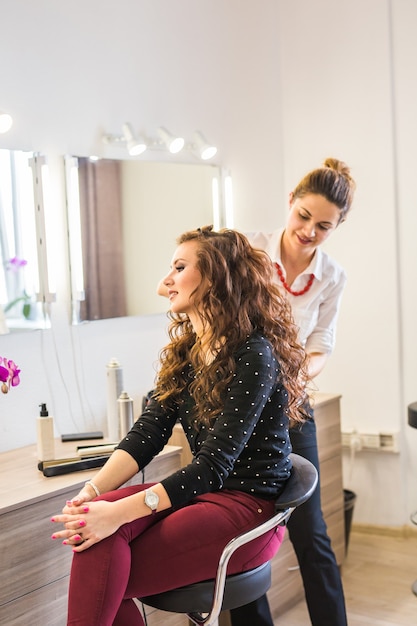 Foto coiffeur de cabeleireiro faz penteado para mulher jovem