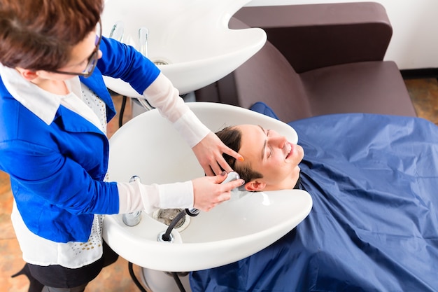 Coiffeur femenino lavar el cabello de los hombres en peluquería