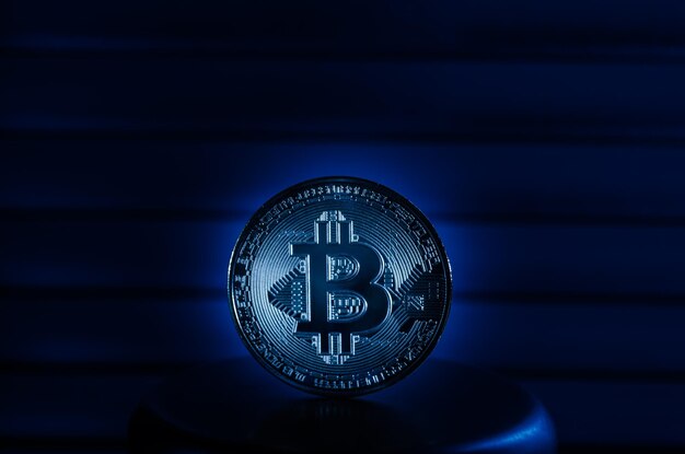 Foto coin cryptocurrency bitcoin en un soporte de metal en primer plano de luz azul