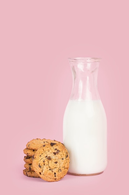 Cokies mit Schokoladenstückchen und einer Flasche Milch auf rosa Hintergrund