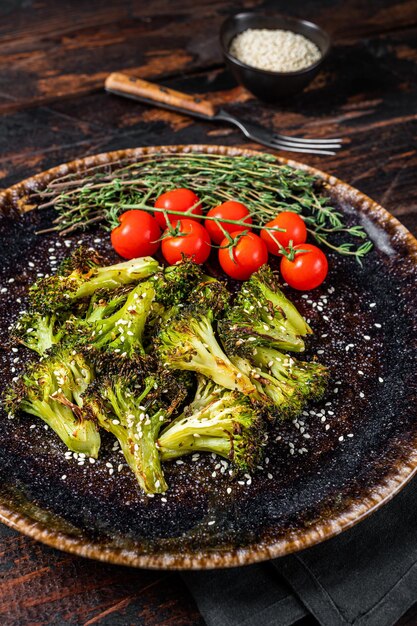 Col de brócoli asado a la parrilla con hierbas en el plato. Fondo de madera. Vista superior.