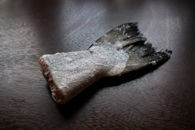 Cola de salmón congelada en una mesa de cocina oscura