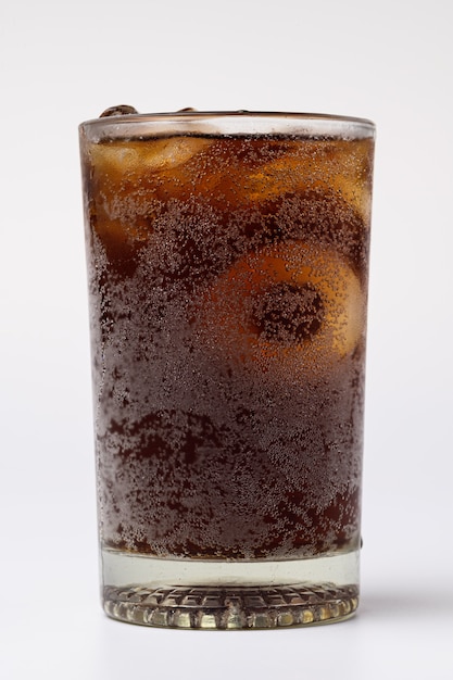 Cola en vaso con cubitos de hielo transparente aislado sobre fondo blanco.