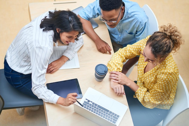 La colaboración entre departamentos hace que una organización funcione sin problemas Captura de un grupo de jóvenes empresarios que usan una computadora portátil en una oficina moderna