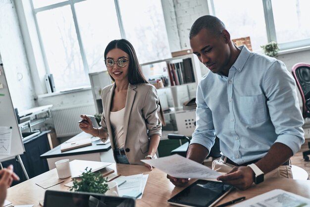 La colaboración es la clave para obtener los mejores resultados. Vista superior de dos colegas de negocios que se comunican y sonríen mientras trabajan en la sala de juntas