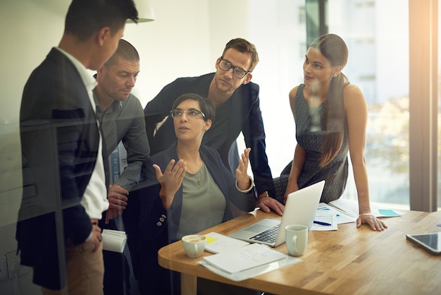 La colaboración nos desafía a articular lo que fue genial en Toma de un grupo de compañeros de trabajo discutiendo algo en una computadora portátil durante una reunión