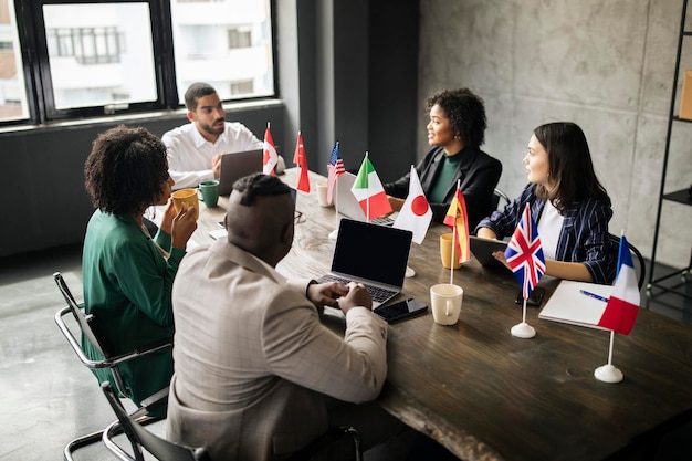 Colaboradores multiculturais homens e mulheres de negócios sentados num escritório moderno