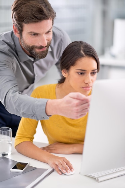 Colaborando em um projeto importante. Dois colegas trabalhando juntos em frente a um computador.