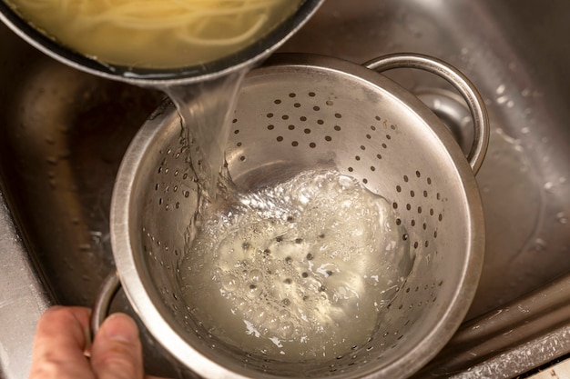 Colador con espaguetis cocidos frescos en la cocina