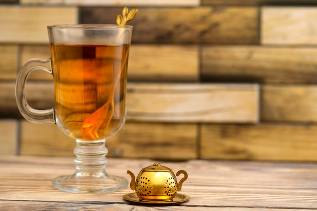 Colador de té vintage y un vaso de té en una mesa de madera con lugar para texto