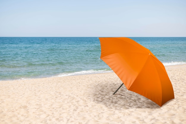 Foto colagem de guarda-chuva laranja na praia