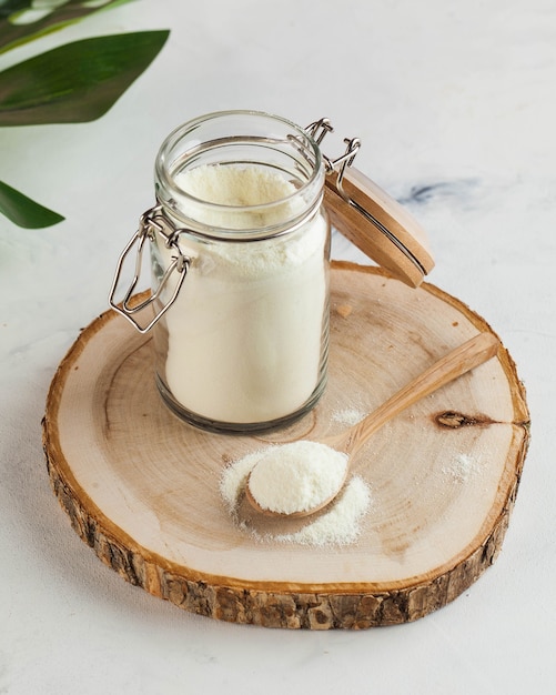 Colágeno na forma de um pó branco em uma jarra de vidro e em uma colher de pau para o rejuvenescimento da pele