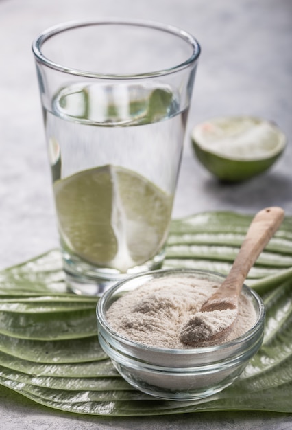 Colágeno en polvo y un vaso de agua con una rodaja de limón; Vitamina C . Los suplementos de colágeno pueden mejorar la salud de la piel al reducir las arrugas y la sequedad.