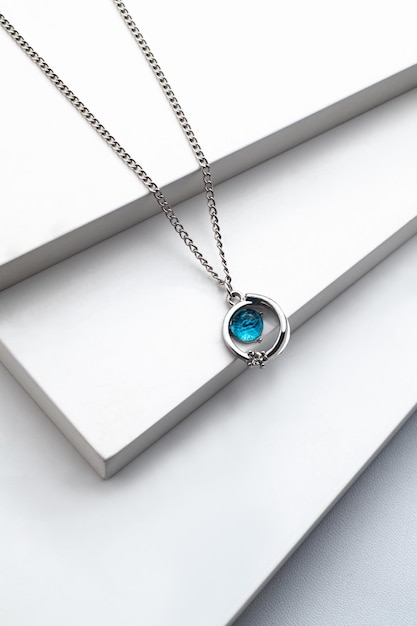 Colar de corrente de prata com pingente de diamante azul sobre fundo branco